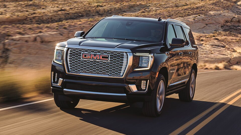 2021 GMC Yukon Denali driving on two-lane road through rugged terrain