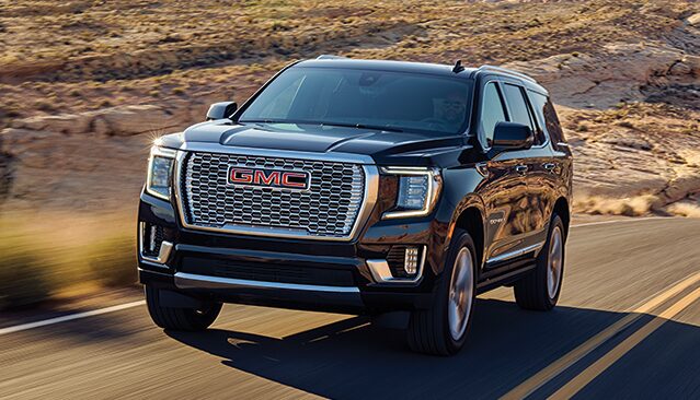 2021 GMC Yukon Denali driving on two-lane road through rugged terrain
