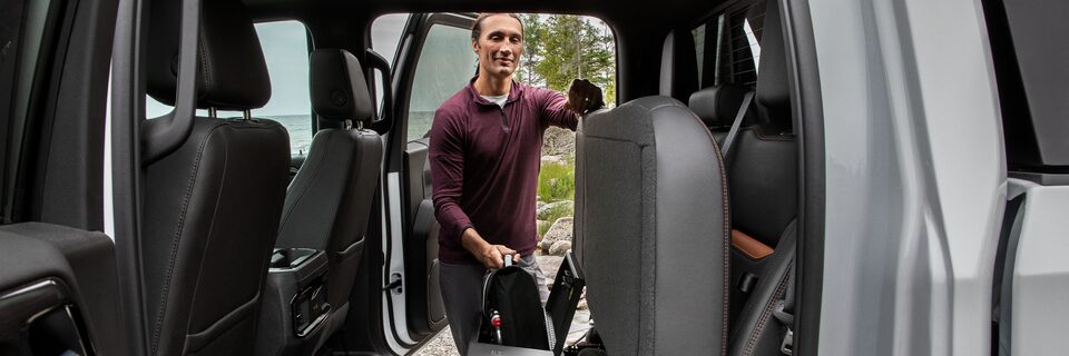 A Man Opening up the Rear Seats to Reveal Additional Cargo Space on a GMC Vehicle