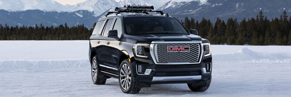 A All Black GMC Denali Parked Off-Road On Snow With Mountains in Background