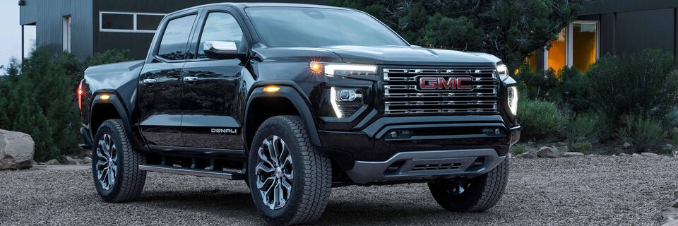 Front Three-Quarters View of a GMC Denali Truck Parked on Gravel in Front of a Home