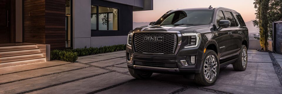 A GMC Denali SUV Parked In Front of a Luxury Home at Sunset