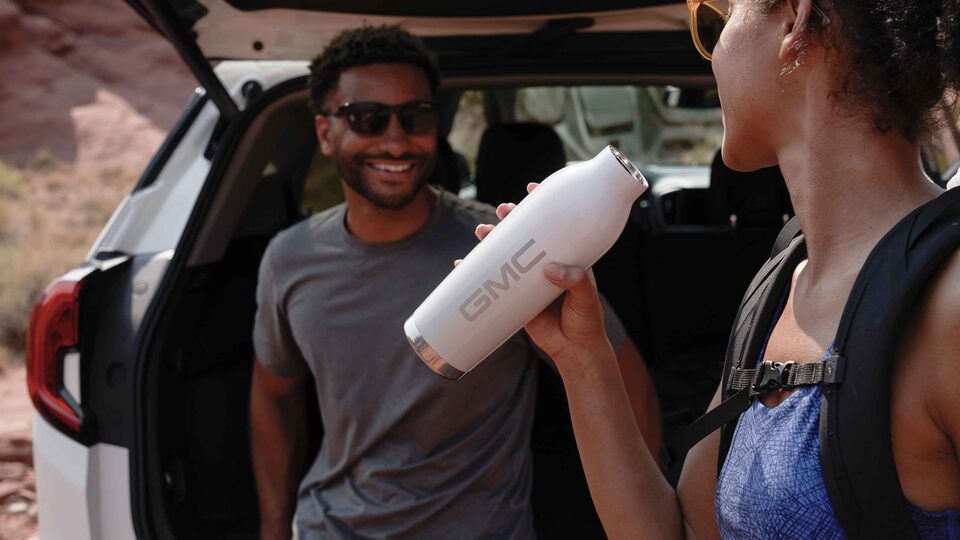 Woman drinking out of a GMC branded reusable water bottle