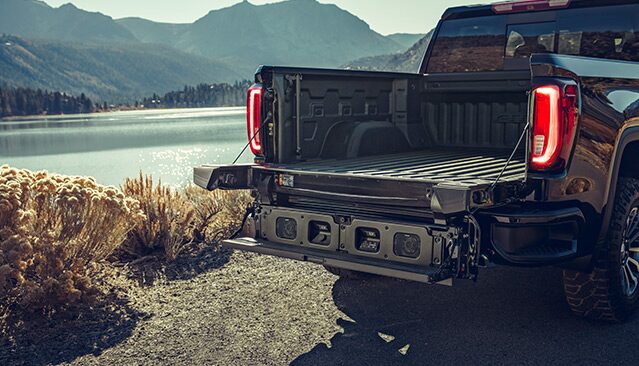 The Open Tailgate of a Black GMC Sierra Pickup Truck With a MultiPro Tailgate System by a Lake