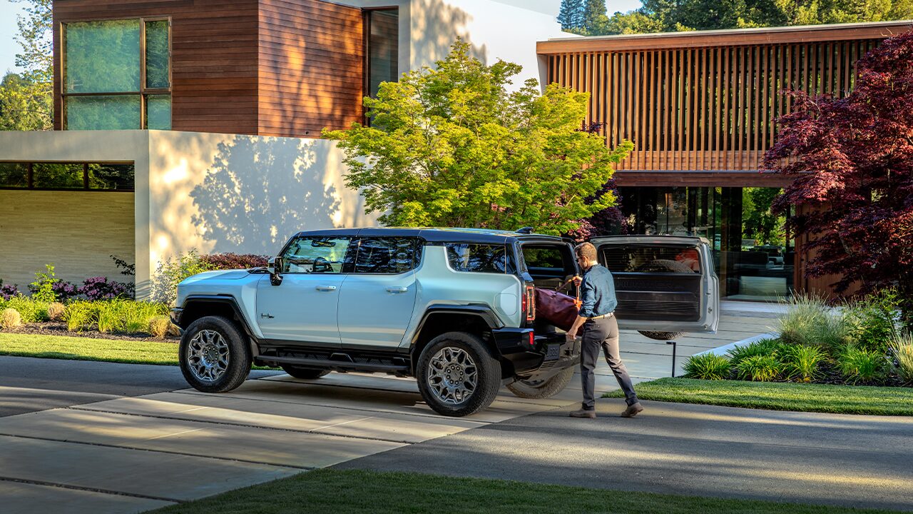 A Man Loading his Luggage into his GMC HUMMER EV SUV Parked on the Street