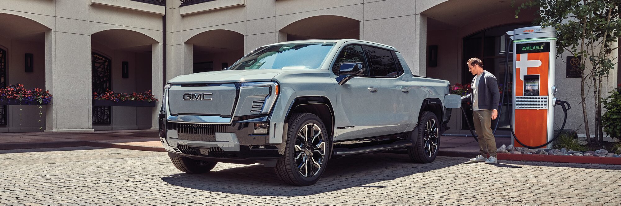 A Man Charging his GMC Sierra EV at a Public Charging Station