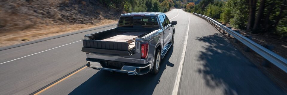 A Man Opening up the Rear Seats to Reveal Additional Cargo Space on a GMC Vehicle
