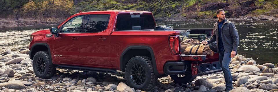 A Man Opening up the Rear Seats to Reveal Additional Cargo Space on a GMC Vehicle