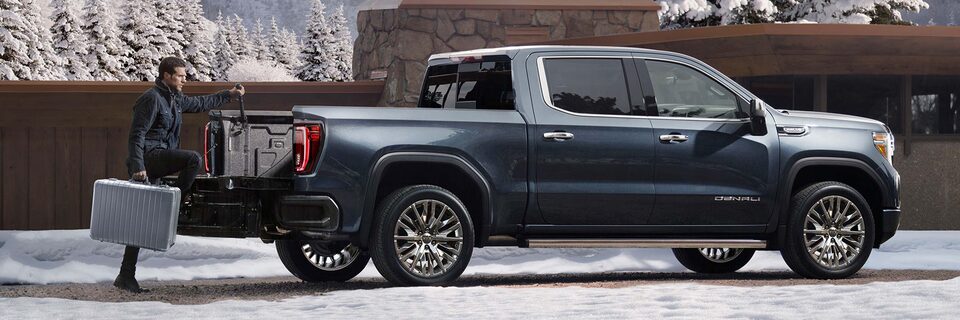 A Man Opening up the Rear Seats to Reveal Additional Cargo Space on a GMC Vehicle