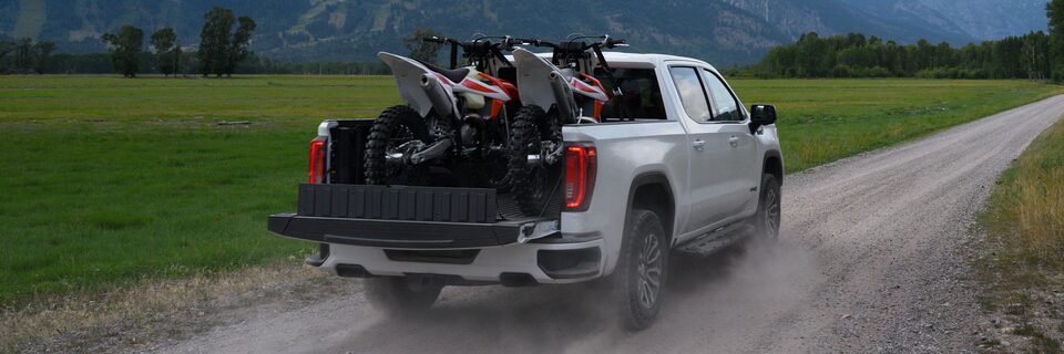 A Man Opening up the Rear Seats to Reveal Additional Cargo Space on a GMC Vehicle