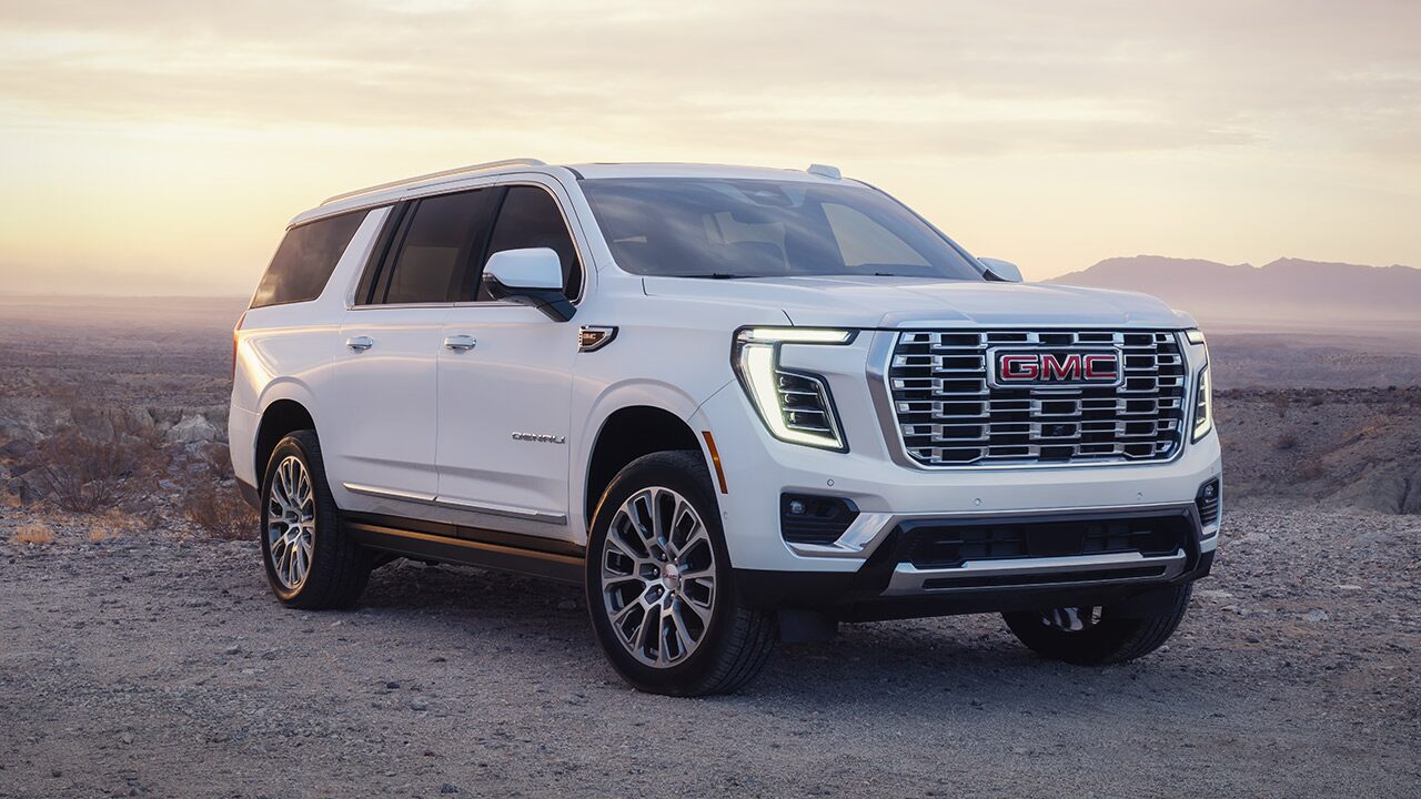Front Three-Quarters View of a White GMC Yukon Large SUV Parked in the Desert at Sunset