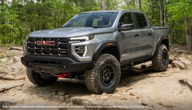 A Gray GMC Canyon AT4X Pickup Truck with Off-Road Tires and Accessories, Parked on a Dirt Trail in a Wooded Area