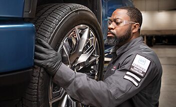 A Certified Technician Installing a New Tire on a Raised Vehicle