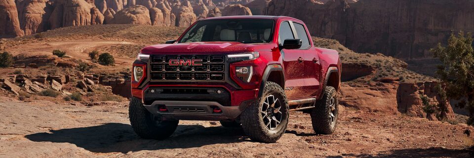 Three-quarters View of a Red 2025 GMC Canyon AT4 Parked on a Rocky Desert Trail After Off-roading