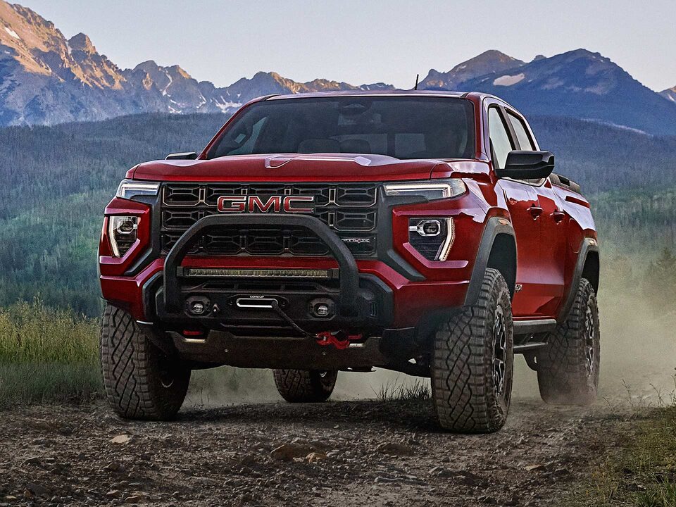 A Red 2025 GMC Canyon AT4 Off-roading on a Rocky Trail Kicking Up Dirt
