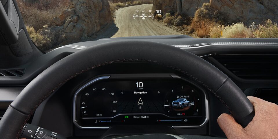 Close-Up View of a Person's Hand on a Steering Wheel with the Head Up Display in Use in a 2025 GMC Sierra HD Pickup Truck