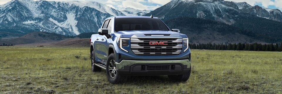 GMC Sierra 1500 Pickup Truck Parked in a Green Valley with Mountains in the Background