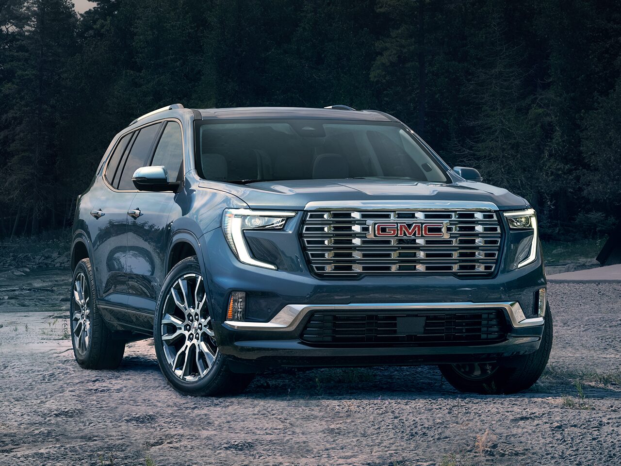 Front Three-Quarters View of a Blue 2026 GMC Acadia Denali Luxury Mid-Size SUV Parked Near a Body of Water