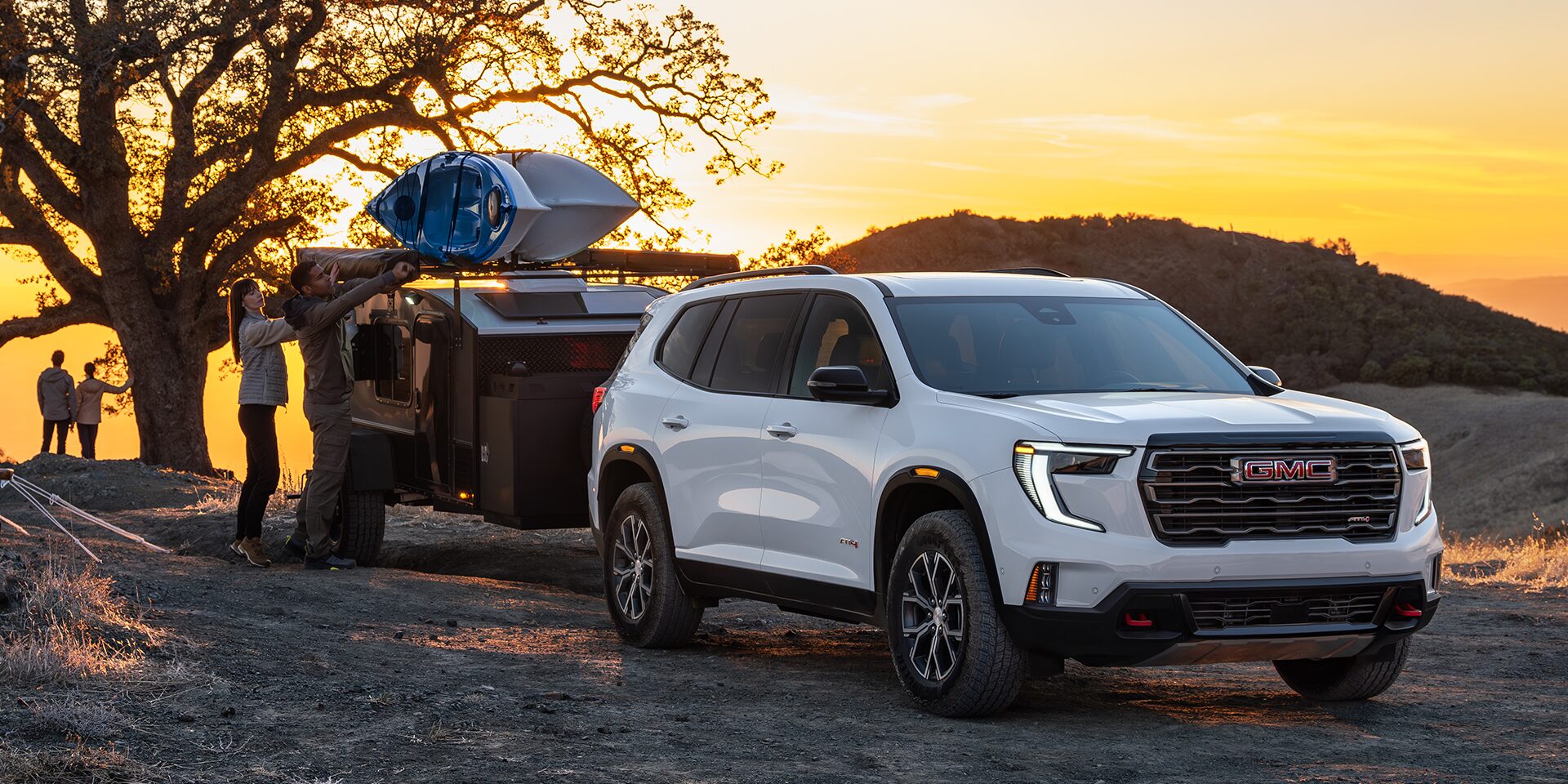 The 2026 GMC Acadia Mid-Size SUV Towing a Trailer over Rough Terrain