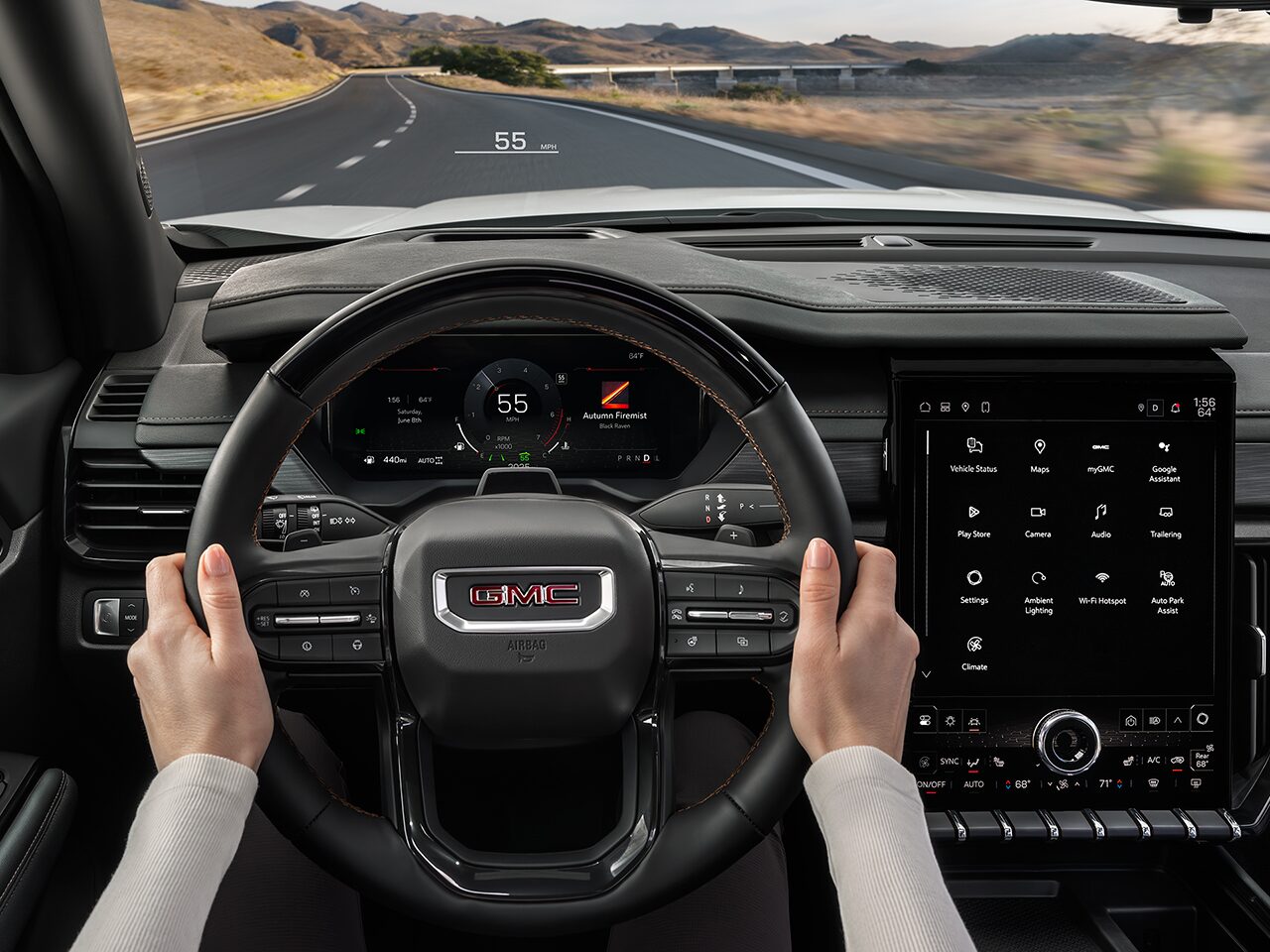 Close-up of the Interior View of a Woman Holding the Steering Wheel and the Infotainment System in the 2026 GMC Acadia