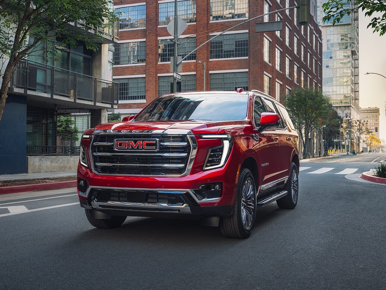 Front Three-Quarter View of the 2026 GMC Yukon Elevation Full-Size SUV Driving Down a City Street