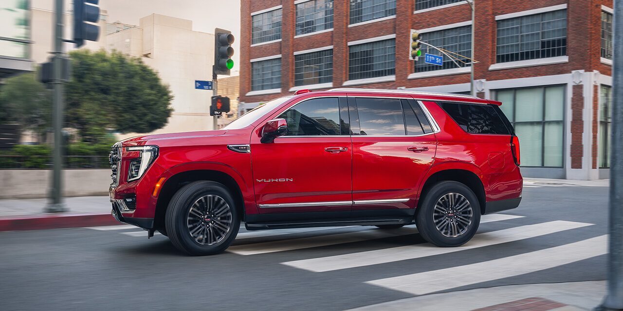 Profile View of a Red Yukon Elevation Full-Size SUV Driving in a City