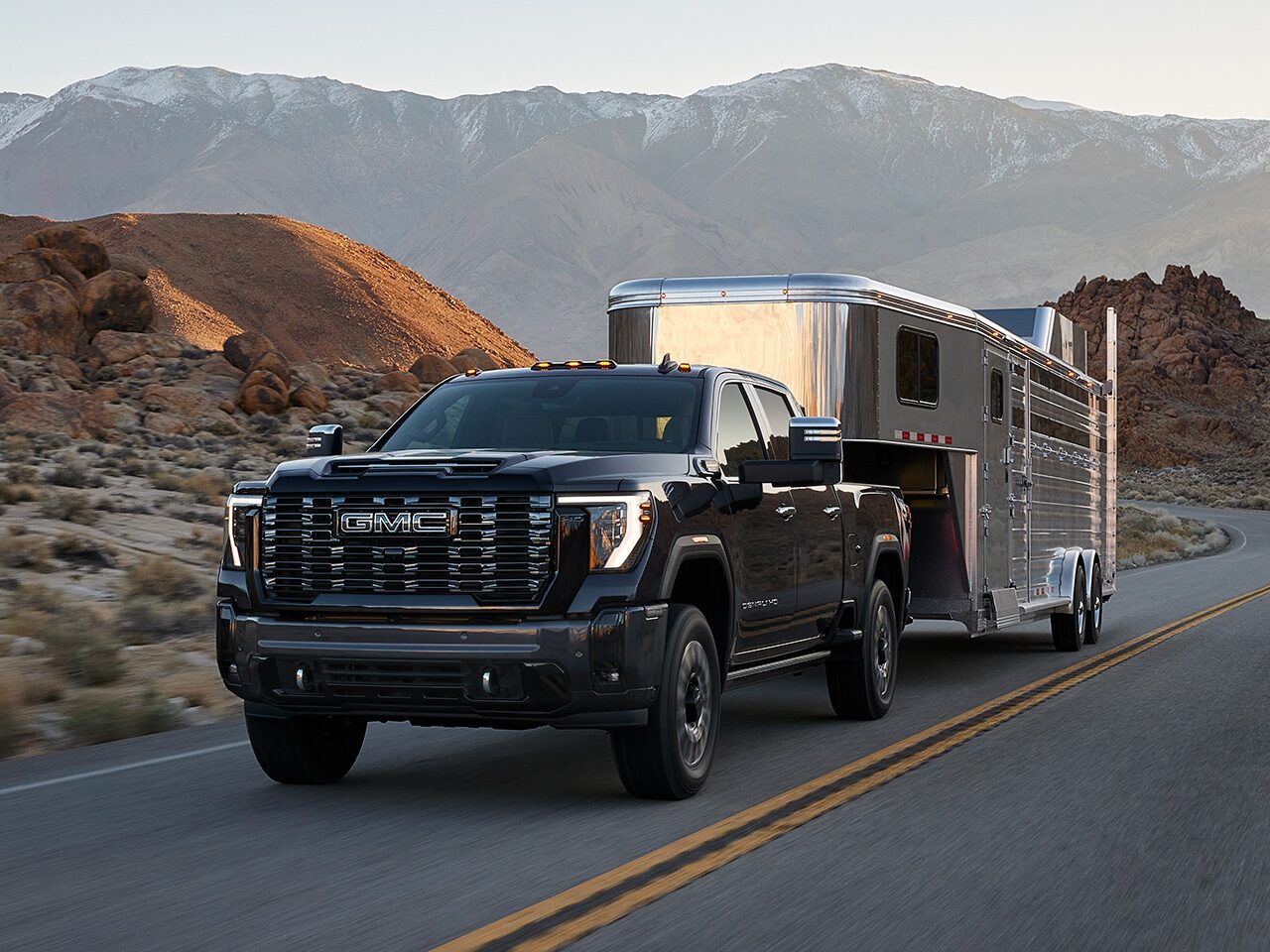 The 2026 GMC Sierra HD Heavy Duty Truck Towing a Trailer Down a Mountain Lined Road
