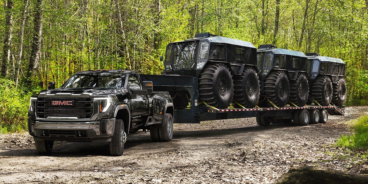 the 2026 GMC Sierra HD Heavy Duty Truck Pulling a Large Piece of Equipment on a Dirt Road
